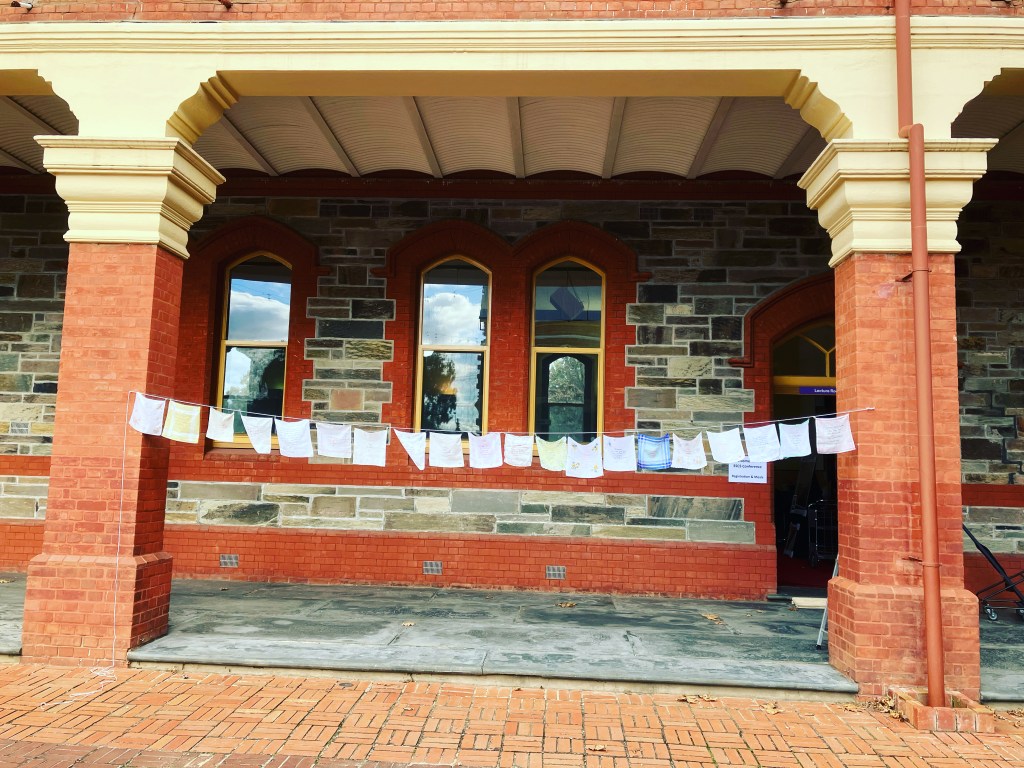A string of hankies between columns on a brick and stone building.